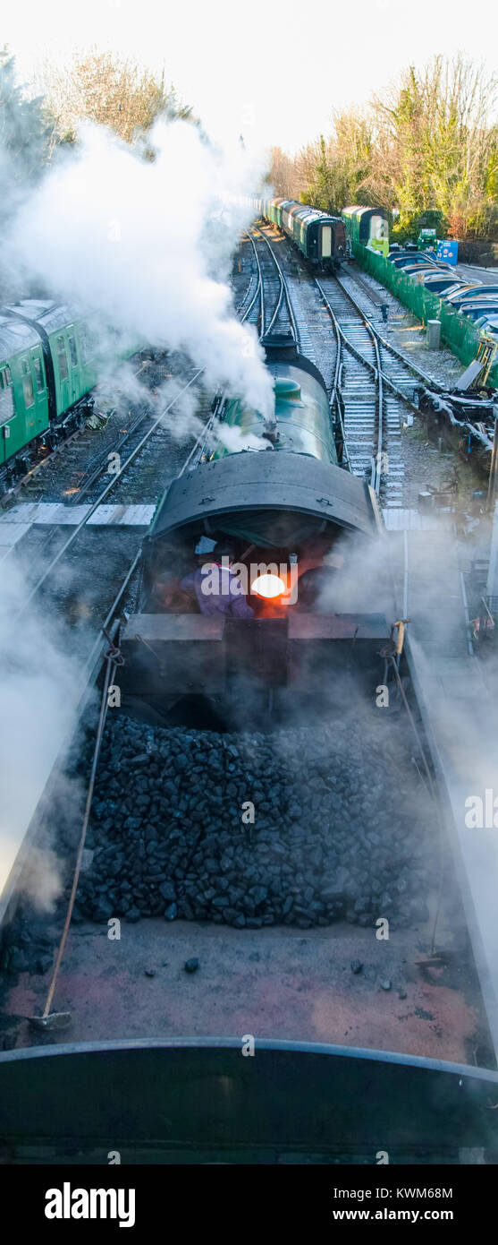 Overhead view of steam engine, tender and footplate showing coal in the tender and the firebox open with driver and fireman - Cheltenham steam engine Stock Photo