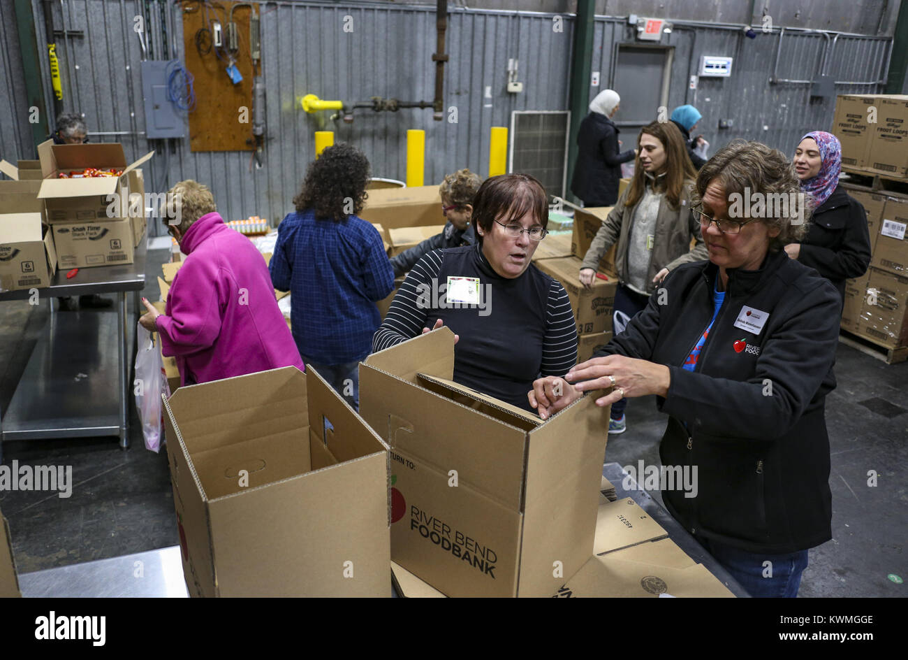 Davenport, Iowa, USA. 4th Dec, 2017. Chapter Leader Gail Karp Volunteer Coordinator Belinda Mielenhausen fold a box together to put bags of food for local students in at River Bend Foodbank in Davenport on Monday, December 4, 2017. The local chapter of the Sisterhood of Salaam Shalom took part in a national event showing solidarity by bringing American Jewish and Muslim women together to perform acts of charity together as a part of National Sadaqah-Tzedakah Day. The chapter chose to focus on hunger insecurity as their focus for this year's project and worked to pack bags of food for kid Stock Photo
