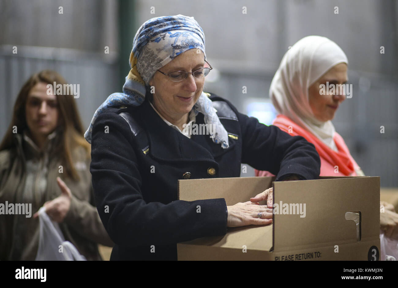 Davenport, Iowa, USA. 4th Dec, 2017. Chapter Leader Lisa Killinger folds a full box packed with bags of food for local students at River Bend Foodbank in Davenport on Monday, December 4, 2017. The local chapter of the Sisterhood of Salaam Shalom took part in a national event showing solidarity by bringing American Jewish and Muslim women together to perform acts of charity together as a part of National Sadaqah-Tzedakah Day. The chapter chose to focus on hunger insecurity as their focus for this year's project and worked to pack bags of food for kids to take home over the weekend while s Stock Photo