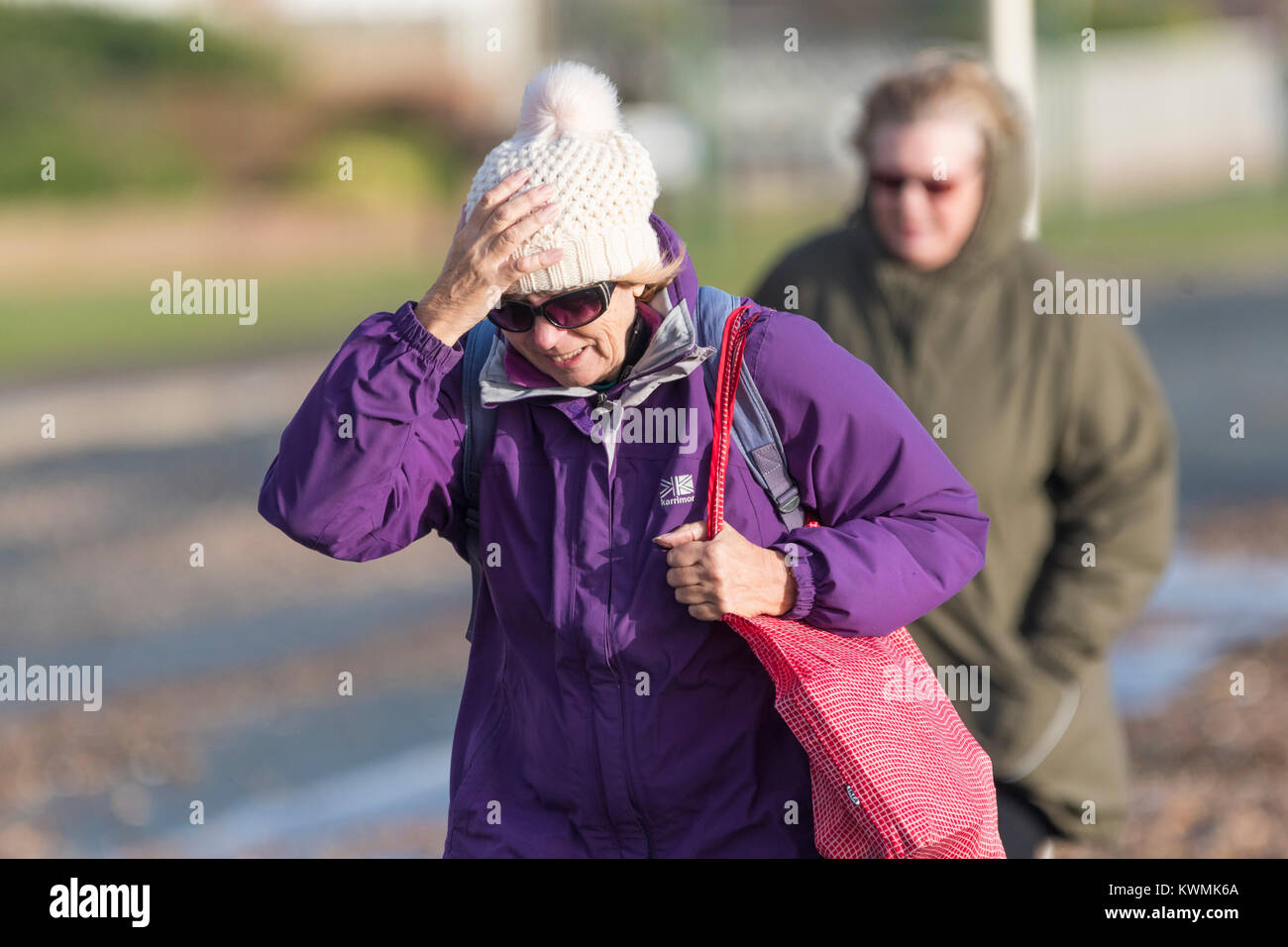 Woman struggling to walk into the wind on a cold Winters day in the UK Stock Photo