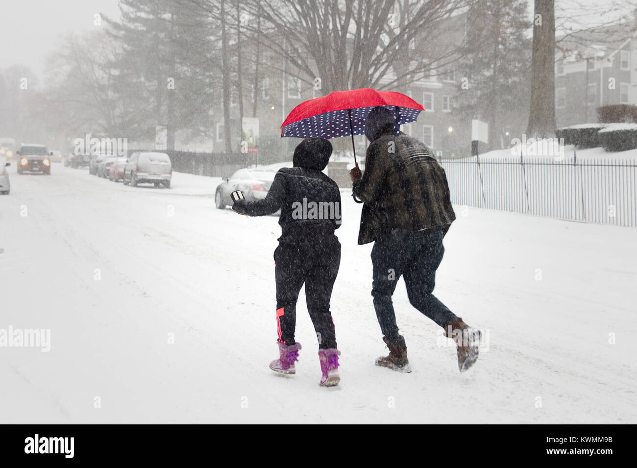 Philadelphia, PA, USA - January 4, 2018: A couple with a red umbrella braves icy gusts as area residents brace for a 'Bomb Cyclone' winter storm in Northwest Philadelphia. Stock Photo
