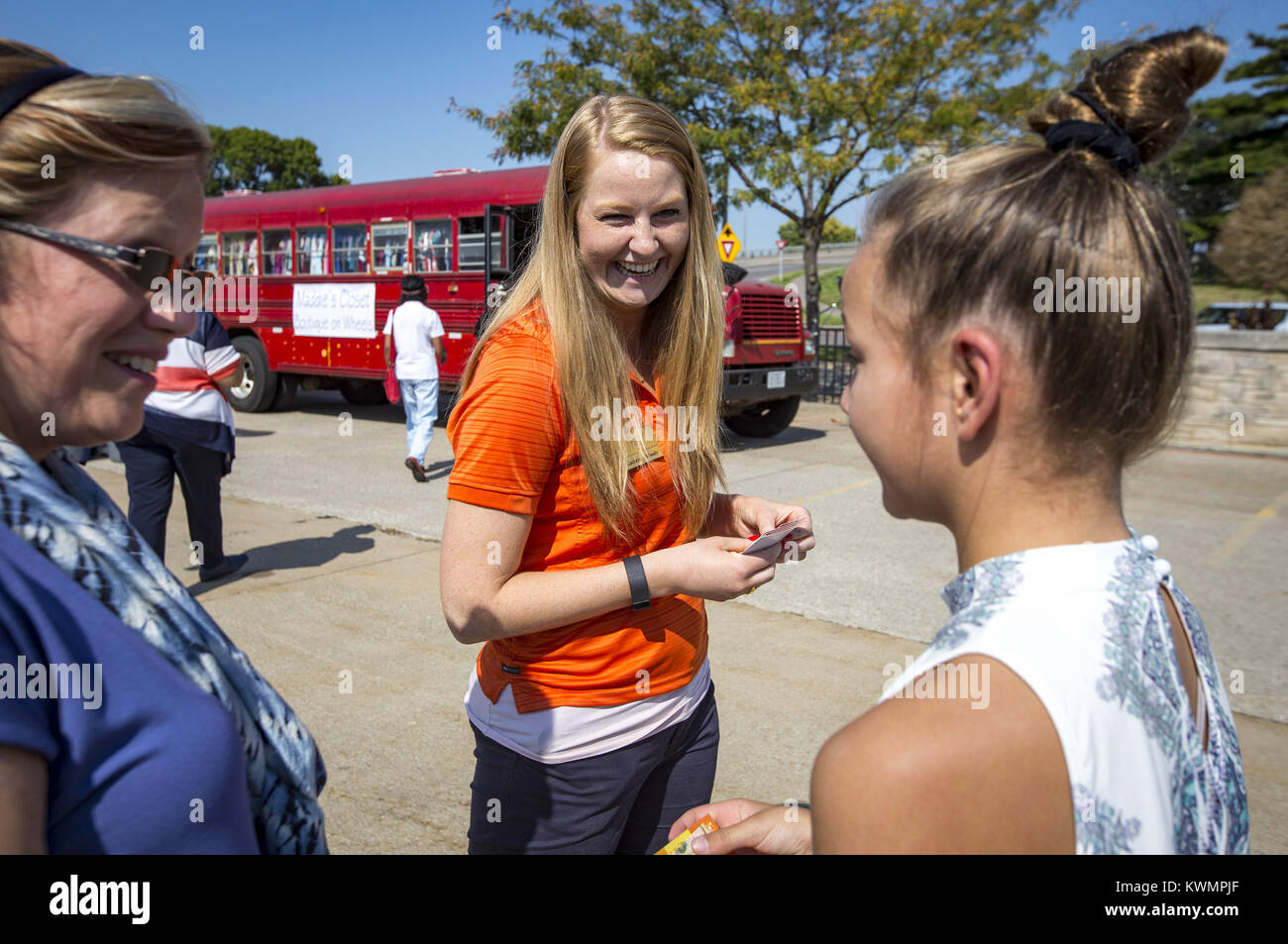 Rock Island, Iowa, USA. 13th Sep, 2017. Employee Katherine Woody hands out ten dollar bills which were given to 50 guests encouraging them to go out and do a random act of kindness for the day at the Royal Neighbors of America Home Office parking lot in Rock Island on Wednesday, September 13, 2017. Kelly Cook of Rock Island and her daughter Madison, 12, were presented with a $10,000 check for the renovation of a donated bus and $5,000 to get them started to cover operating costs. The mother-daughter duo has been collecting donated clothes to give to young kids in need and was previously Stock Photo
