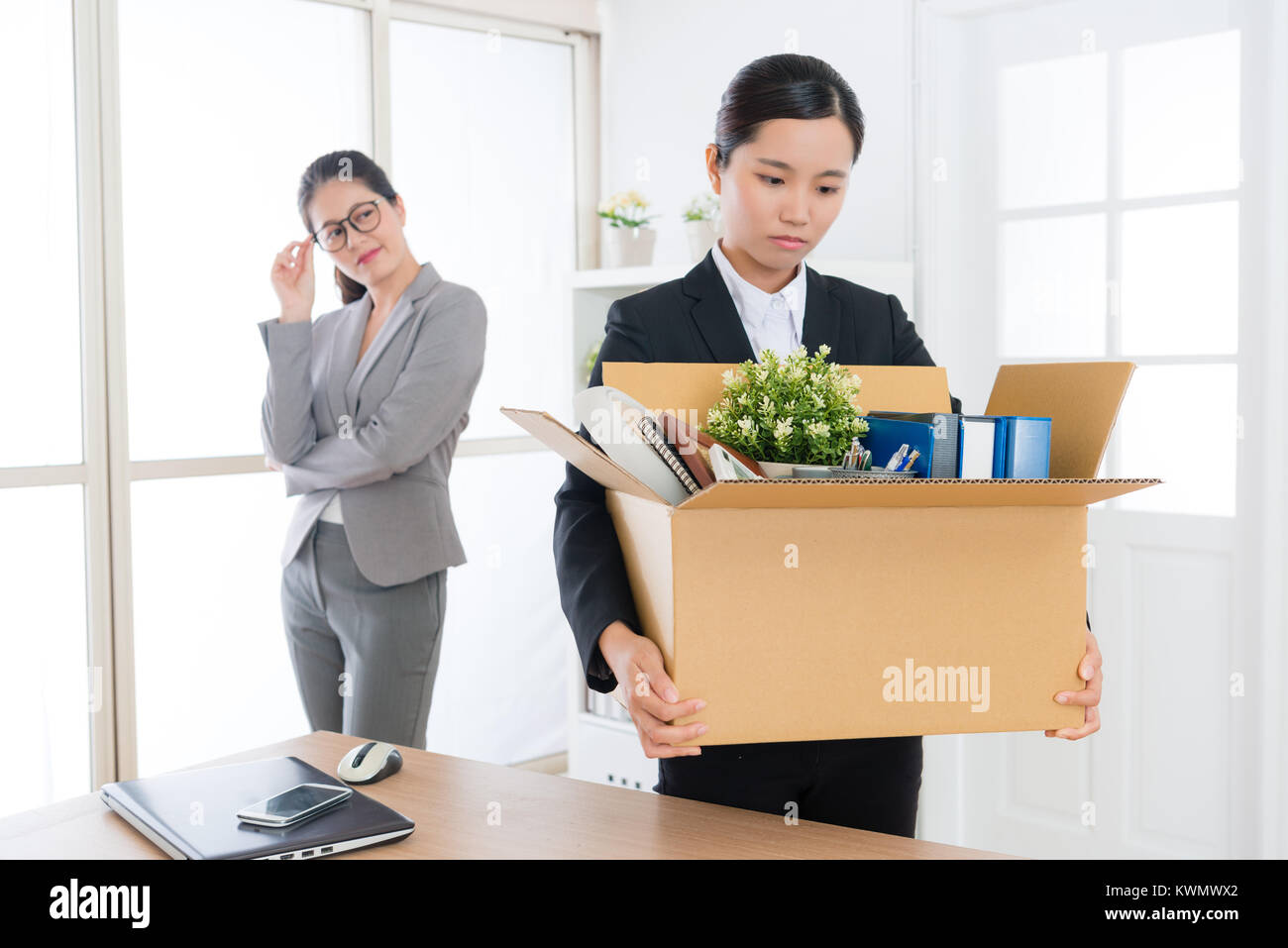 happy elegant company manager woman feeling cheerful when her colleague girl receives layoff message and ready leaving company. Stock Photo