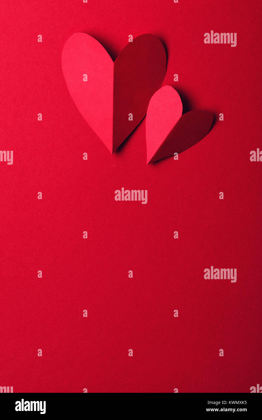 Red paper love heart on a plain red background. Valentines day romance background Stock Photo