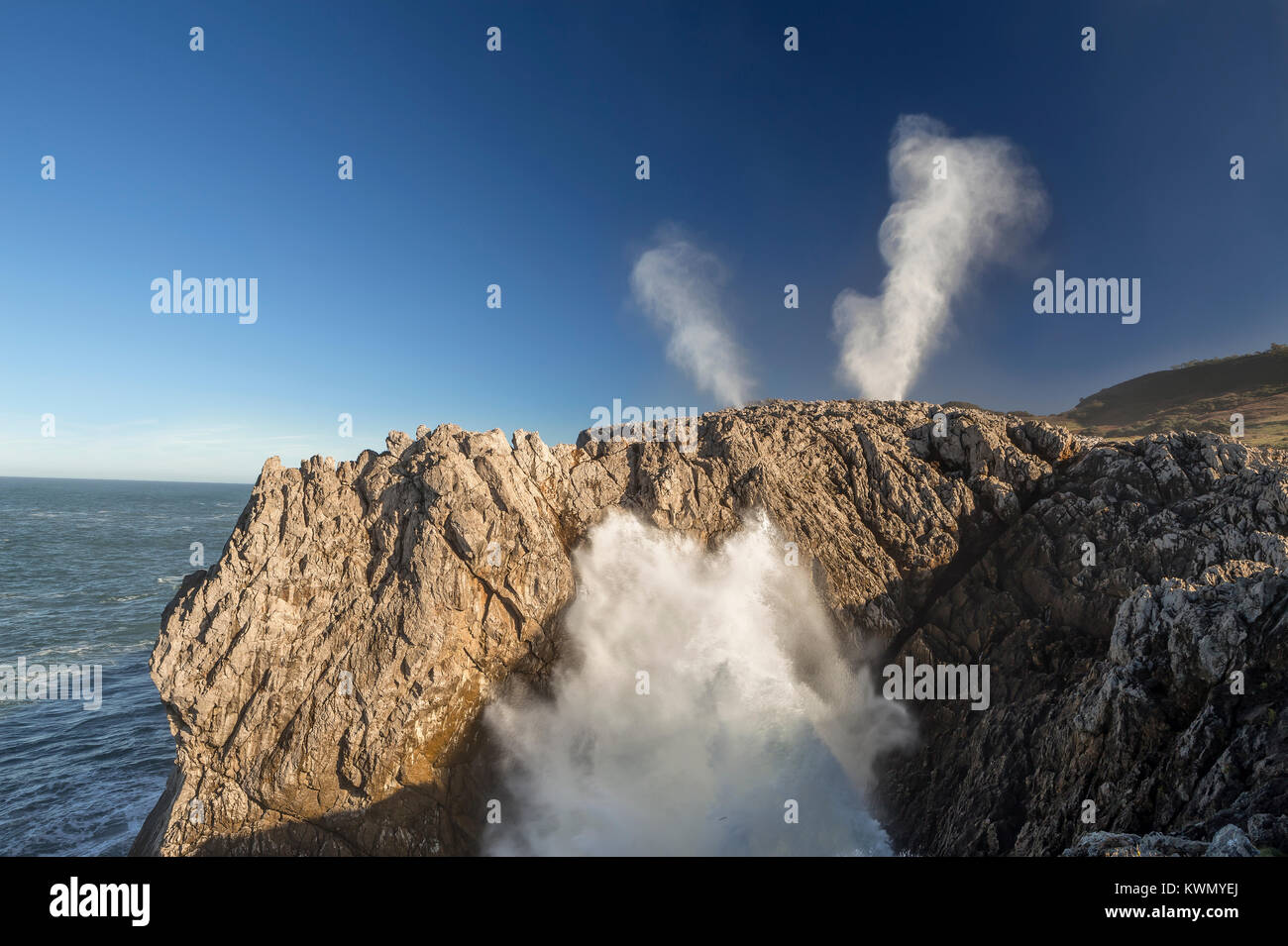 Waves crushing against a cliff and geysers Stock Photo