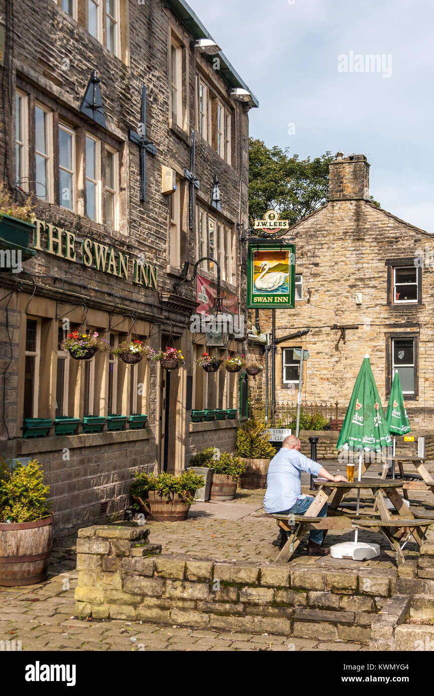 Man enjoys a beer in the sunshine outside the Swan Inn, Uppermill, Oldham, England, United Kingdom Stock Photo