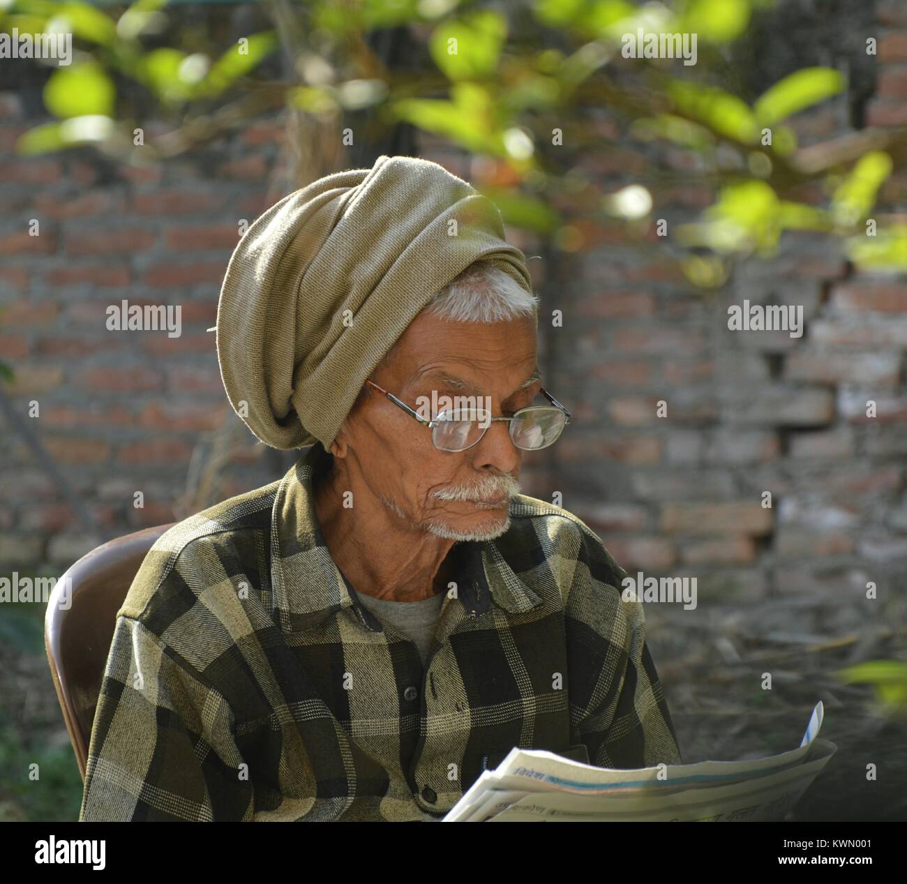 Grandpa studying newspaper in garden early morning. Stock Photo