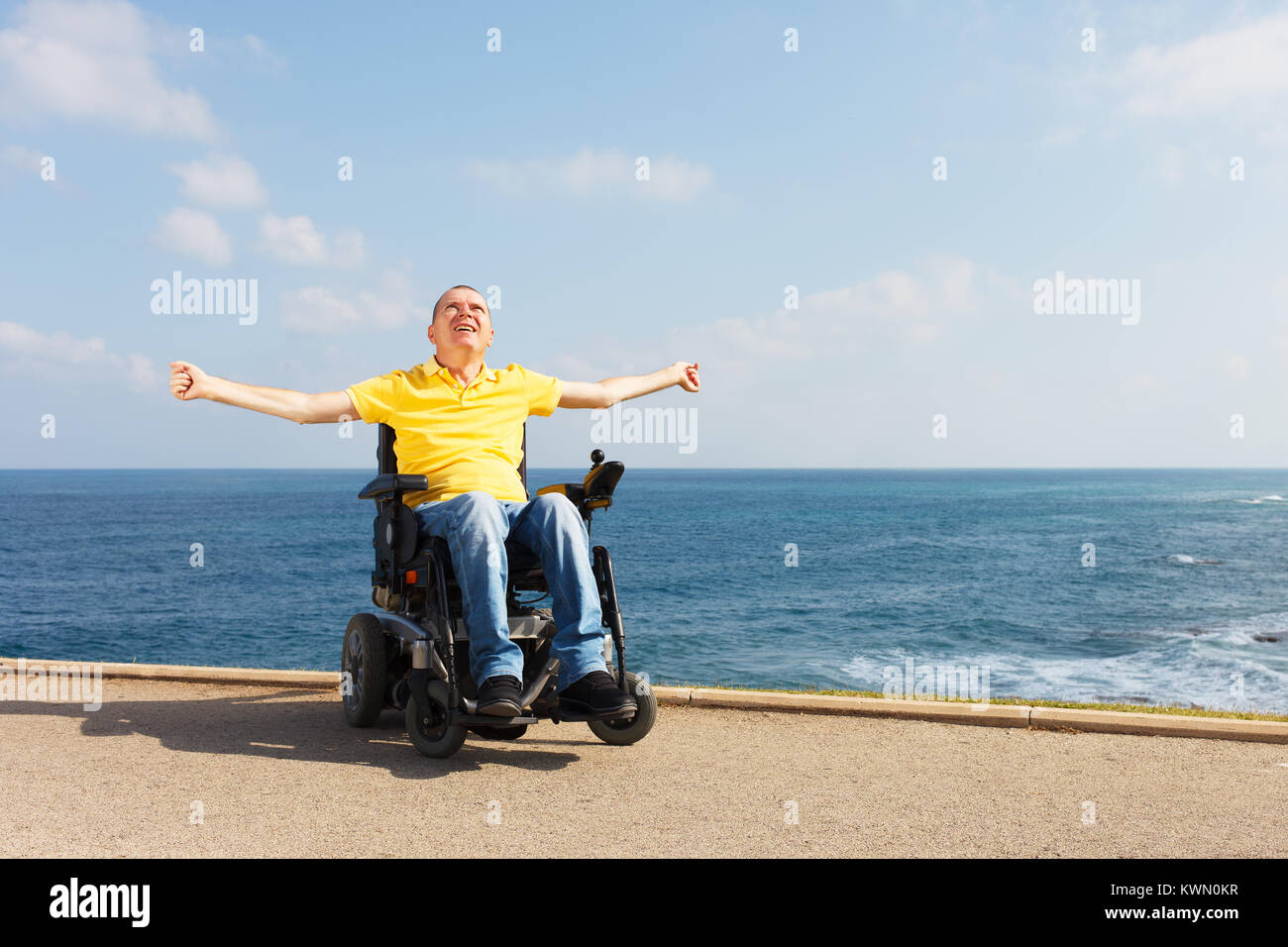Disabled man sitting in wheelchair showing freedom. Stock Photo