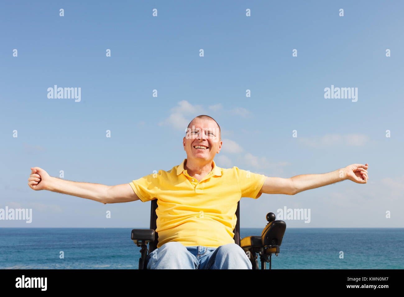 Disabled man sitting in wheelchair showing freedom. Stock Photo