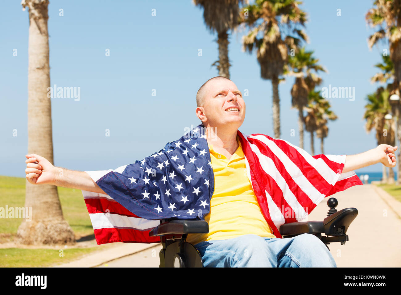 Disabled man sitting in wheelchair with flag of USA showing freedom Stock Photo