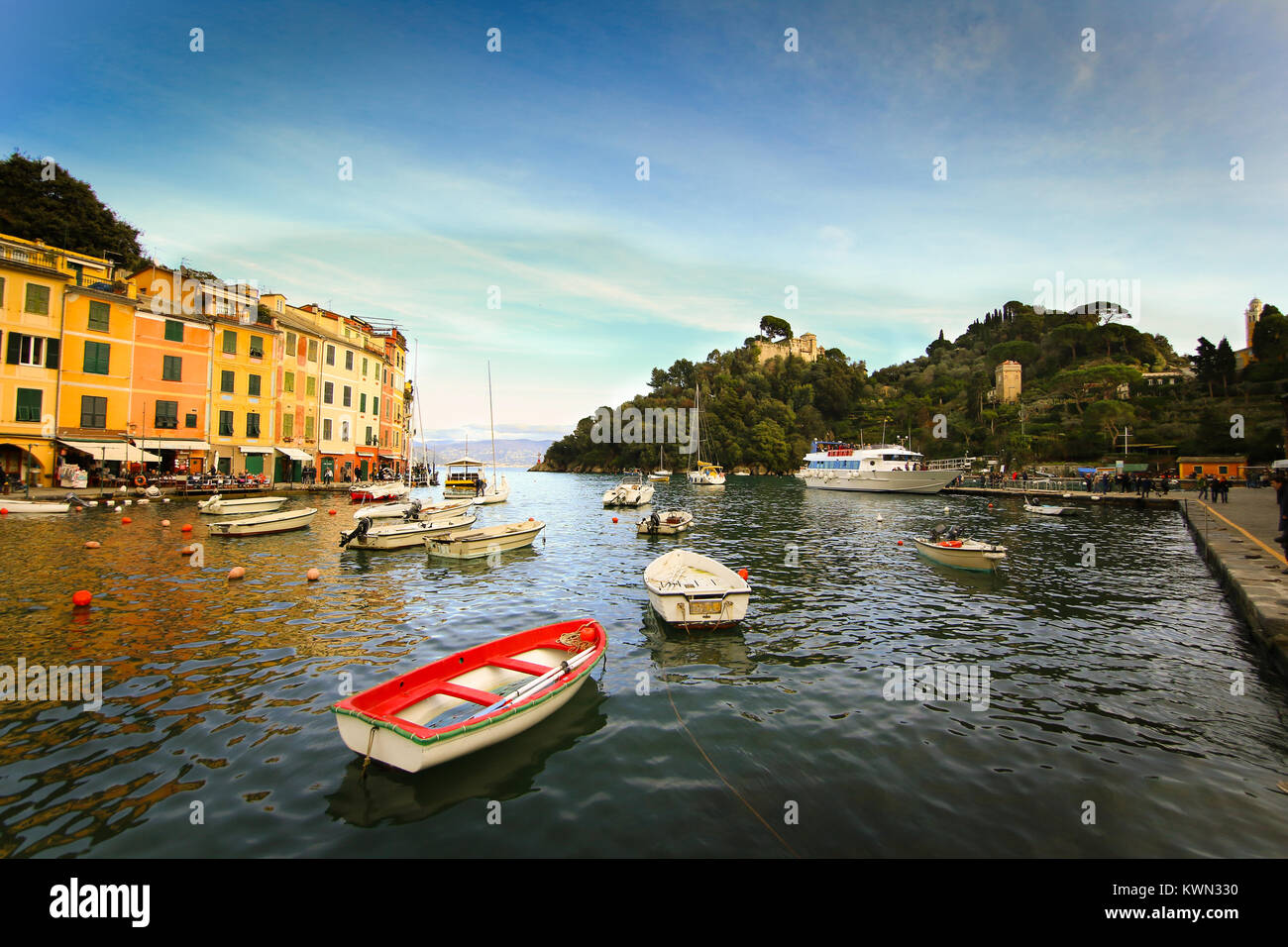 Colorful buildings on the promenade of Portofino with boats floating in the marina and blue sky background Stock Photo