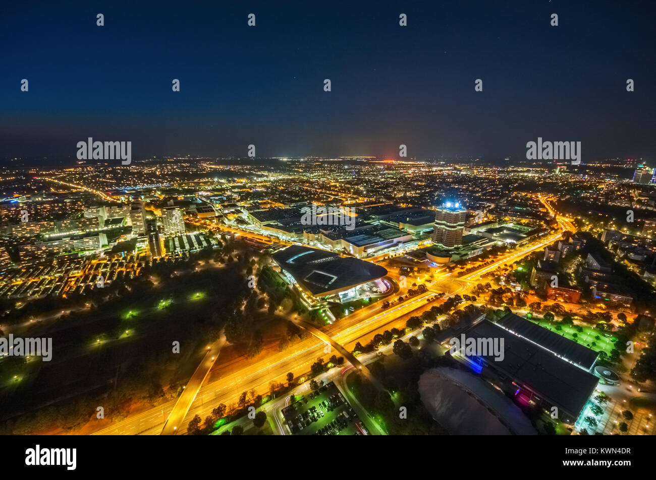 Aerial view of the illuminated Munich Olympic Village and the BMW Headquarters at night. Munich, Germany. Stock Photo