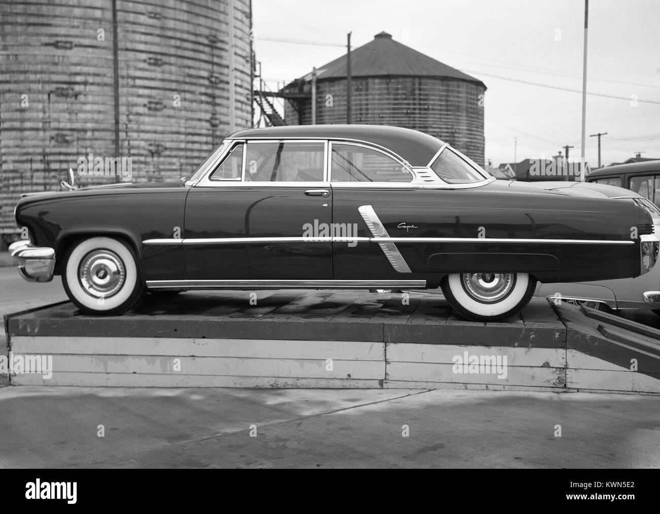 A then-new Lincoln Capri automobile is displayed on a pedestal with silos in the background, at Henderson Center Motors, a car dealership in Eureka, California, 1950. Stock Photo