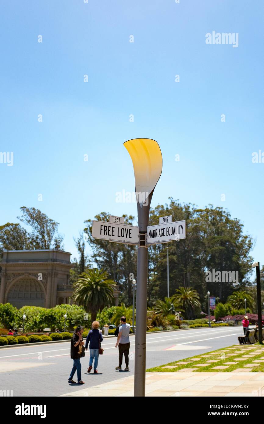 A mock street sign reads 1967 Free Love, 2017 Marriage equality, demonstrating the connection between historical and contemporary social issues in the city, with tourists walking past, at the De Young art museum in Golden Gate Park, San Francisco, California, July 11, 2017. Stock Photo