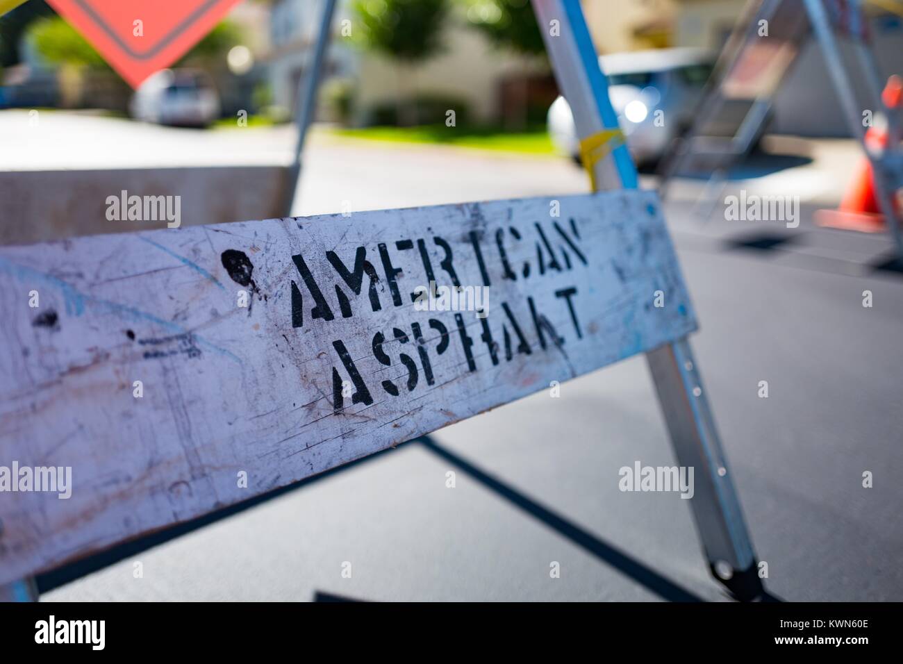 Closeup of the base of a metal road construction sign with spray paint stencil reading American Asphalt, San Ramon, California, July 11, 2017. Stock Photo