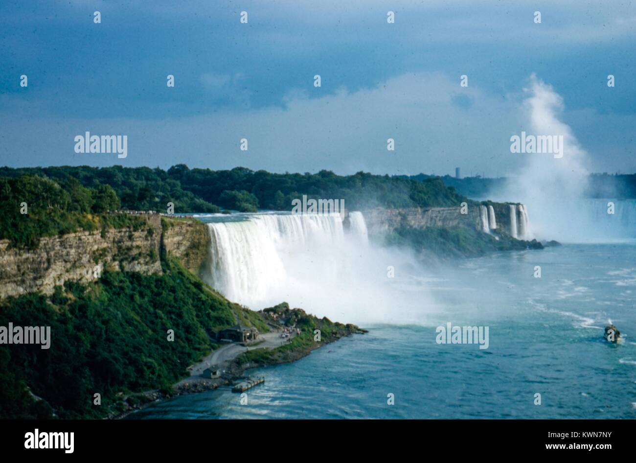 Water pours over the falls at Niagara Falls, with mist and a tourist
