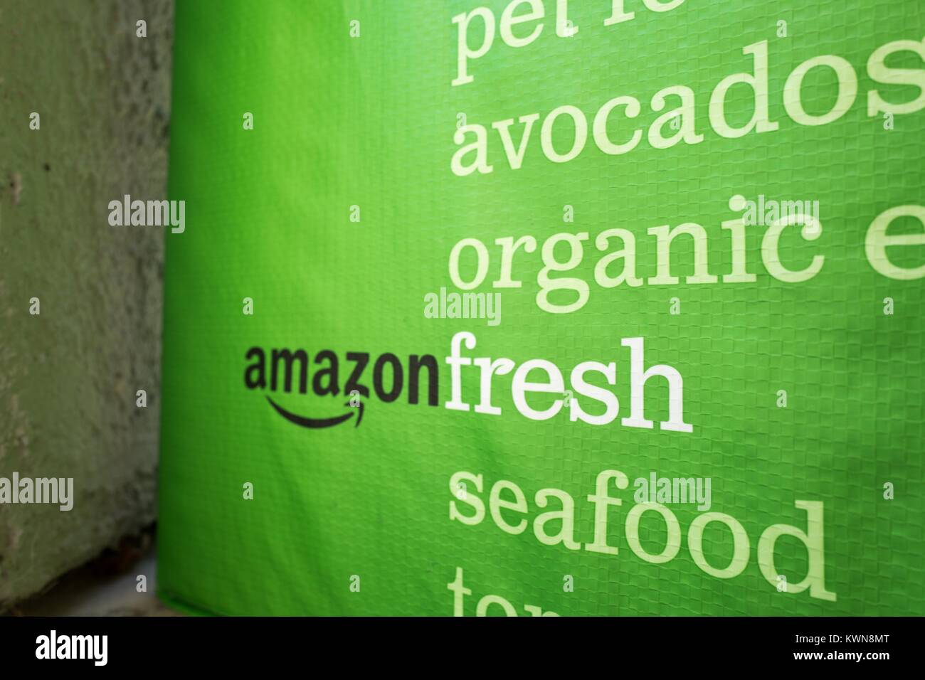 Green cold pack tote for Amazon Fresh grocery delivery service, with Amazon logo and text listing groceries which may be ordered using the service, on the doorstep of a suburban home in the San Francisco Bay Area town of San Ramon, California, July 26, 2017. In June of 2017, Amazon announced that it would acquire the upscale grocery chain Whole Foods Market to expand its offerings in the grocery industry. Stock Photo