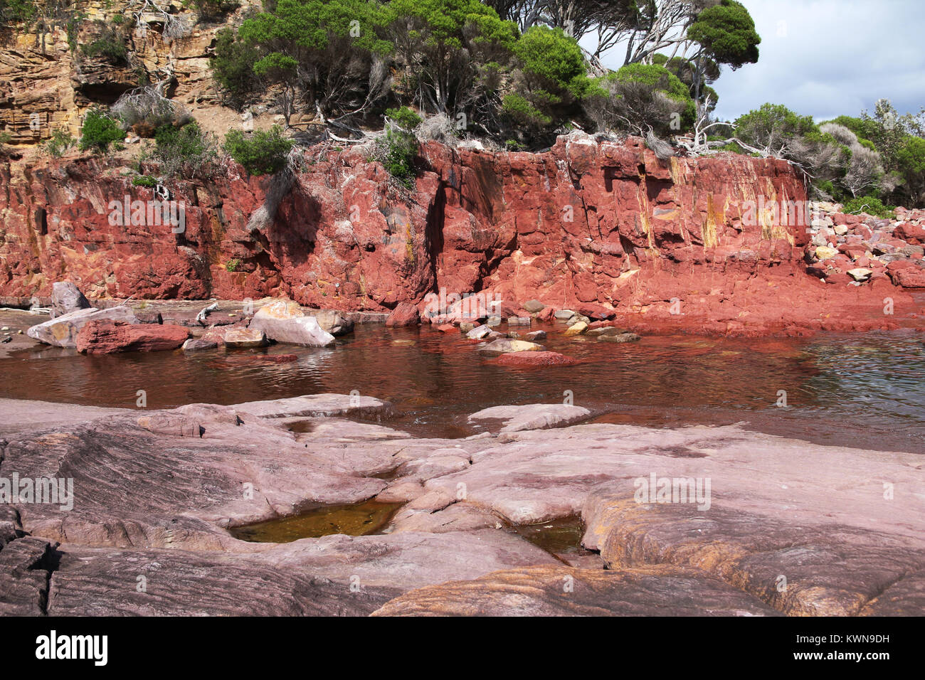 Ancient red rock forms cliff face near Bittangabee Bay in Ben Boyd National Park, Eden, NSW, Australia. Travel photography, regional Australia. Stock Photo