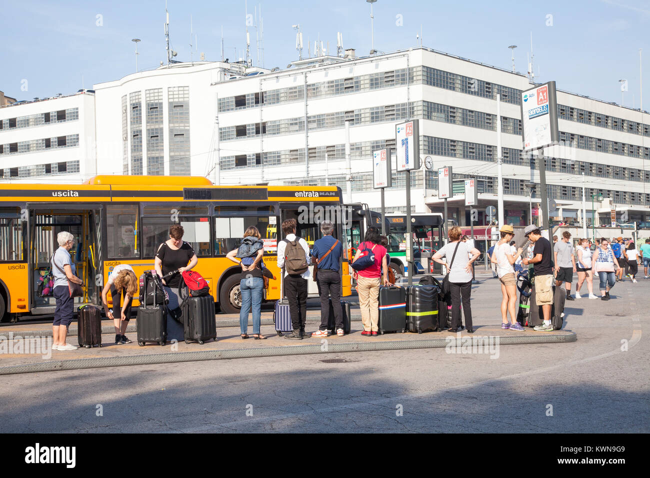 Tourists waiting  with their luggage to catch a bus to the airport in Piazzale Roma, Santa Croce, Venice, Italy Stock Photo