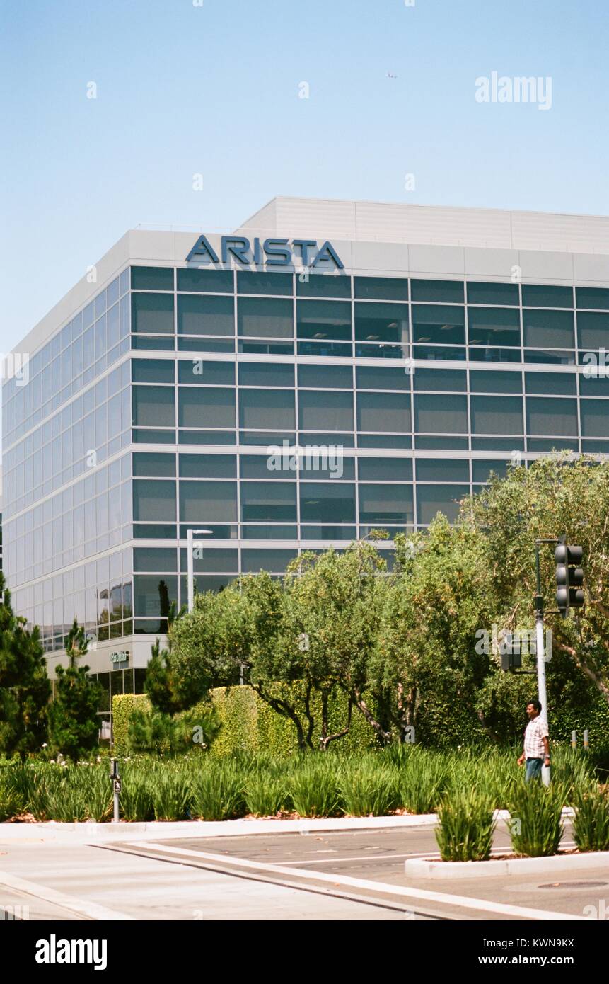 A man is visible walking through a landscaped area, with logo and signage, at the headquarters of networking technology company Arista in the Silicon Valley town of Santa Clara, California, July 25, 2017. Stock Photo