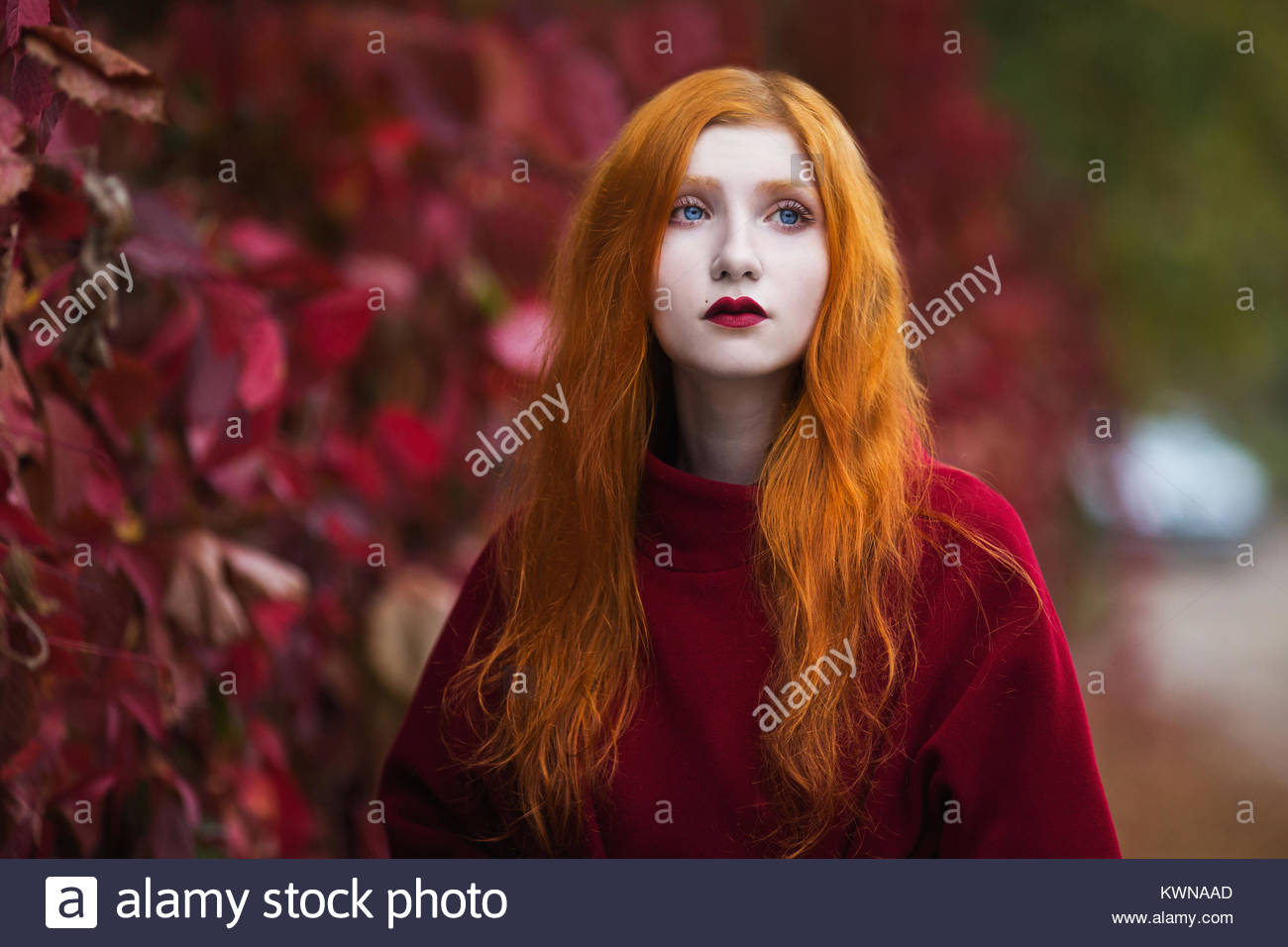 Woman With Red Straight Hair In A Red Coat On A Bright Autumn
