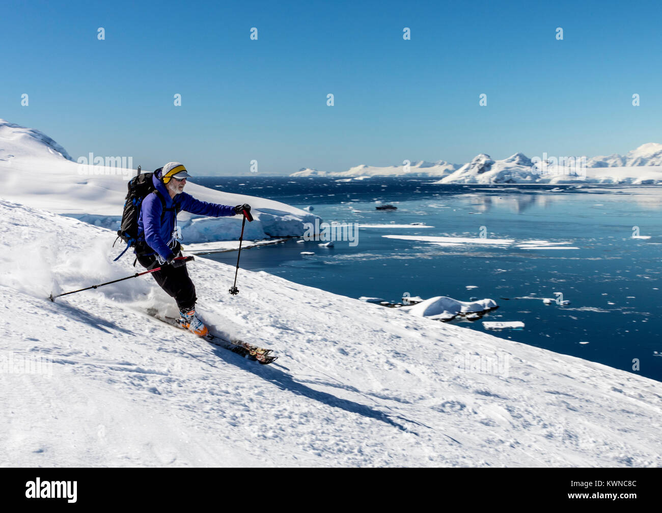 Alpine ski mountaineers skiing downhill; Nansen Island; Antarctica Stock Photo