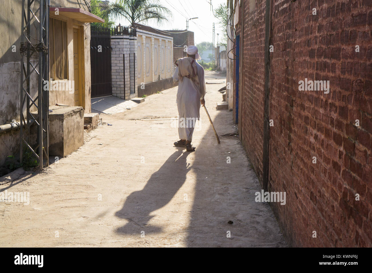Rear view of an old Pakistani man walking in an alley Stock Photo
