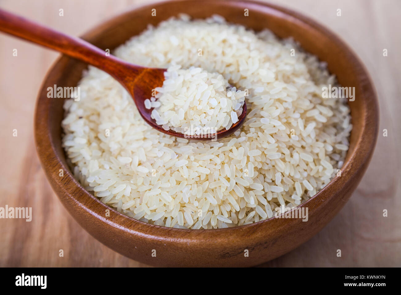 Raw long-grain steamed rice in a bowl on a wooden background. Ingredient for a healthy diet. Stock Photo