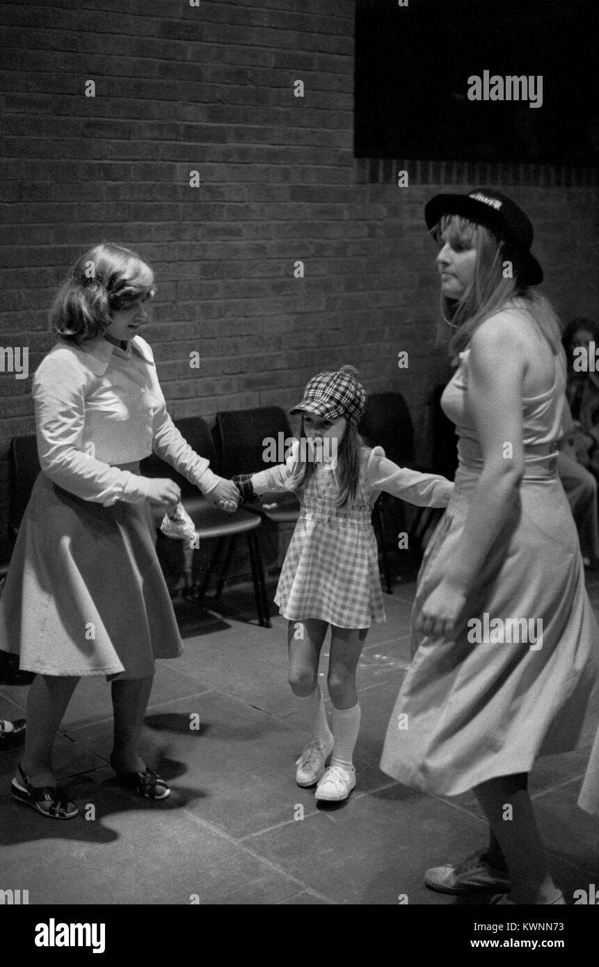 Youth Club 1970s UK. Disco dancing at the Timebridge Youth club. Teen girls dancing sisters looking after their younger sister dancing with her to disco music.  The Wells Fargo Disco.  Chells, Stevenage, Hertfordshire. 1975 England HOMER SYKES. Stock Photo