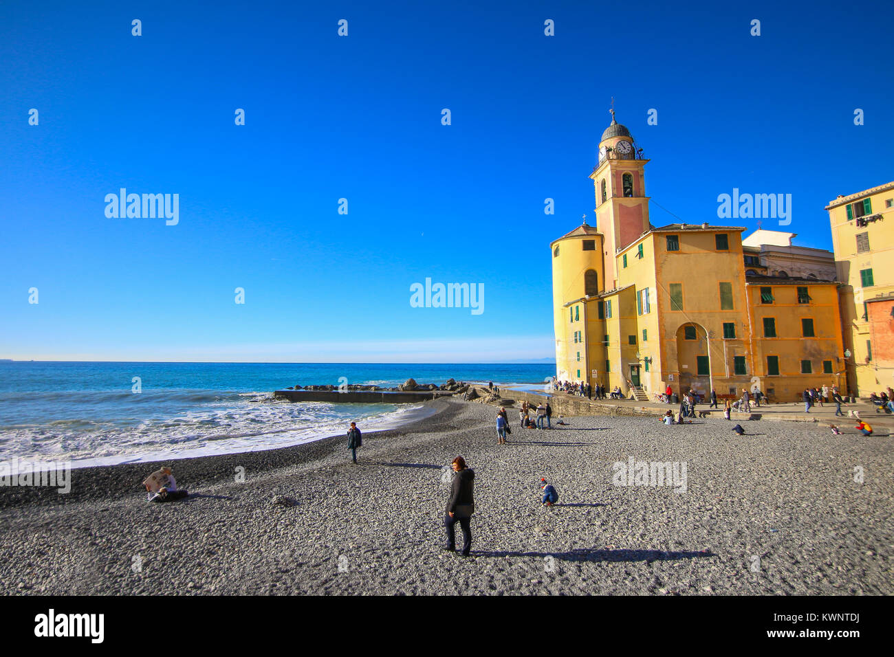 Camogli, Italy - People relaxing on the beach and the basilica Santa Maria Assunta in the background Stock Photo
