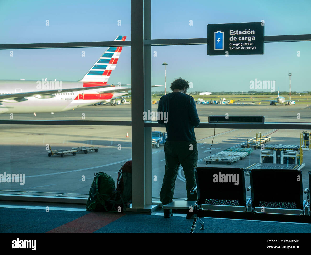 Traveler waiting at gate; charging station for smart phone; commercial jet airplane; Ministro Pistarini International Airport; Ezeiza; Buenos Aires; A Stock Photo