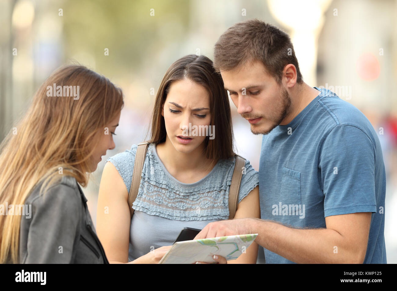 Couple of three worried tourists asking for help to a girl on the street Stock Photo