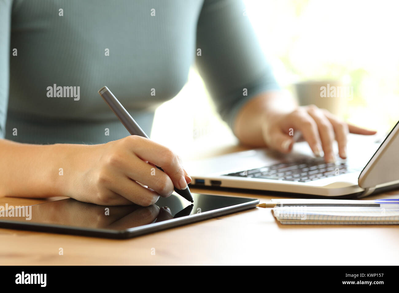 Close up of a woman hands working with a laptop and drawing in a digital tablet on a dek at home or office Stock Photo