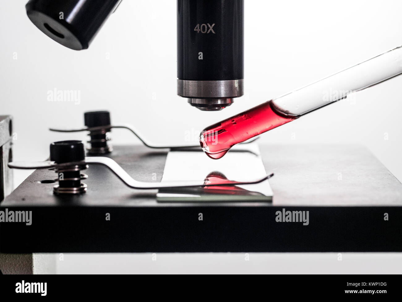 Pipette, dropper placing a red blood substance droplet on a microscope ...