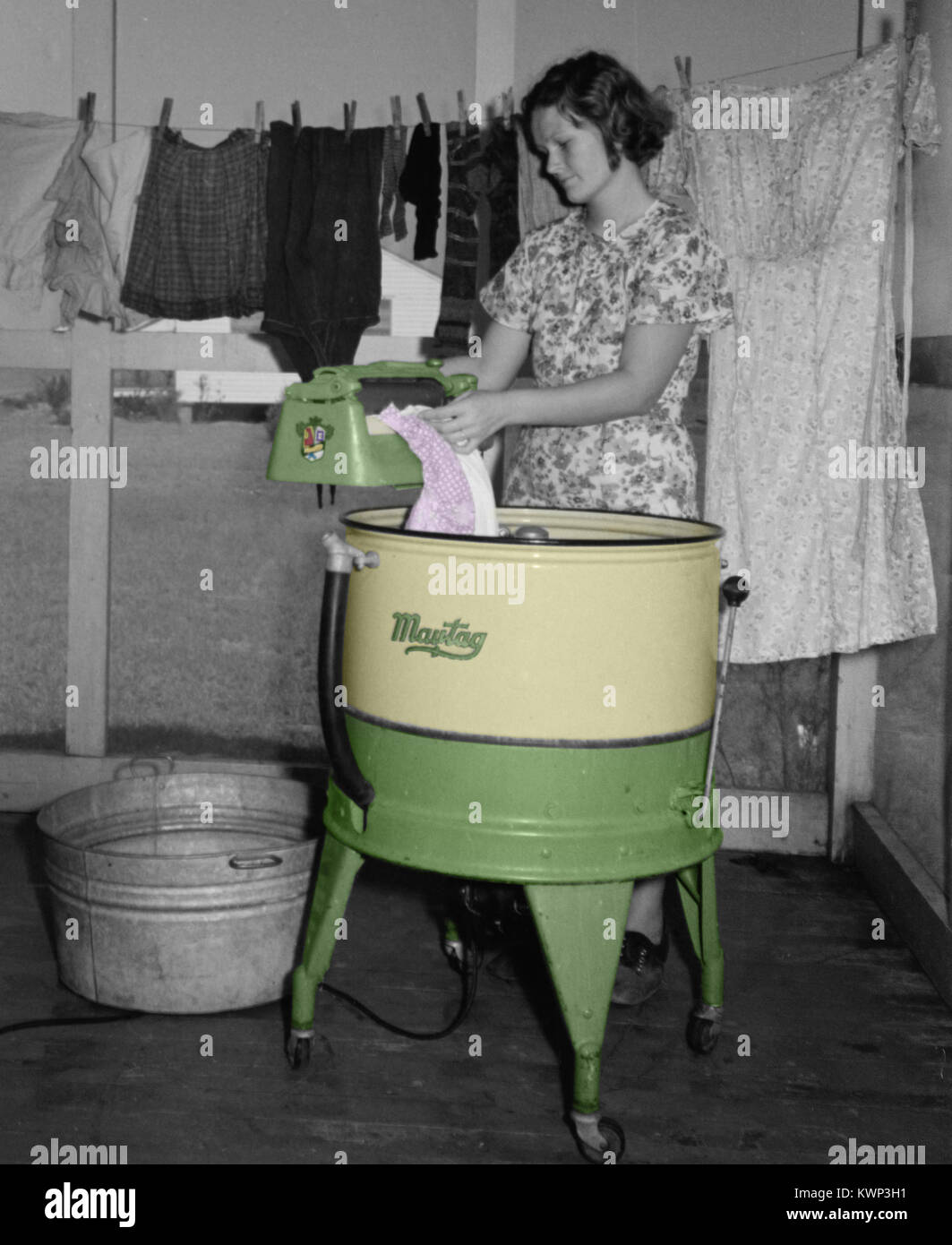 Woman washing clothes with an antique wringer washing machine circa 1939. Stock Photo