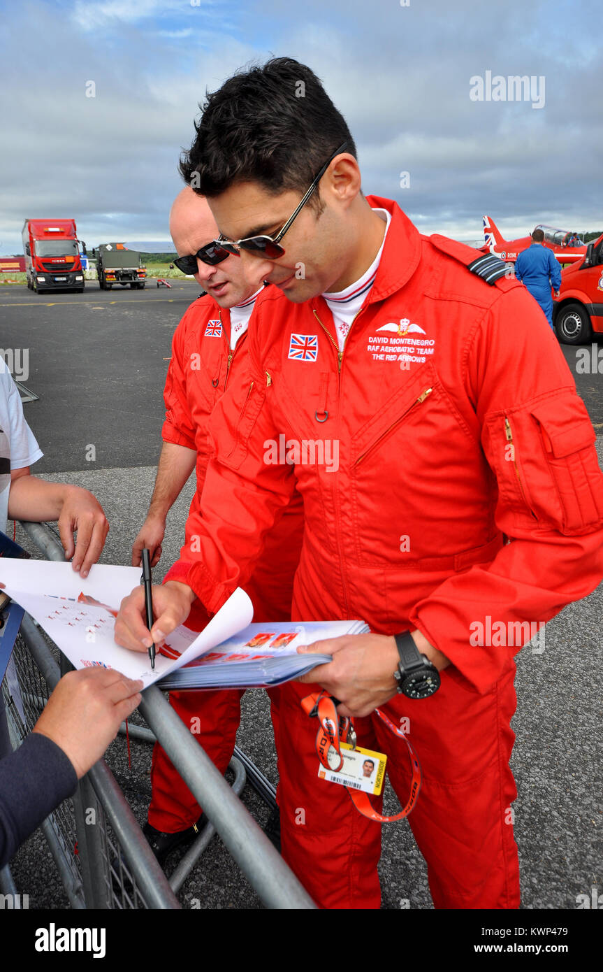 David Montenegro, Red 1 team leader of RAF Red Arrows signing autographs for fans at an airshow. Pilot Steve Morris behind Stock Photo