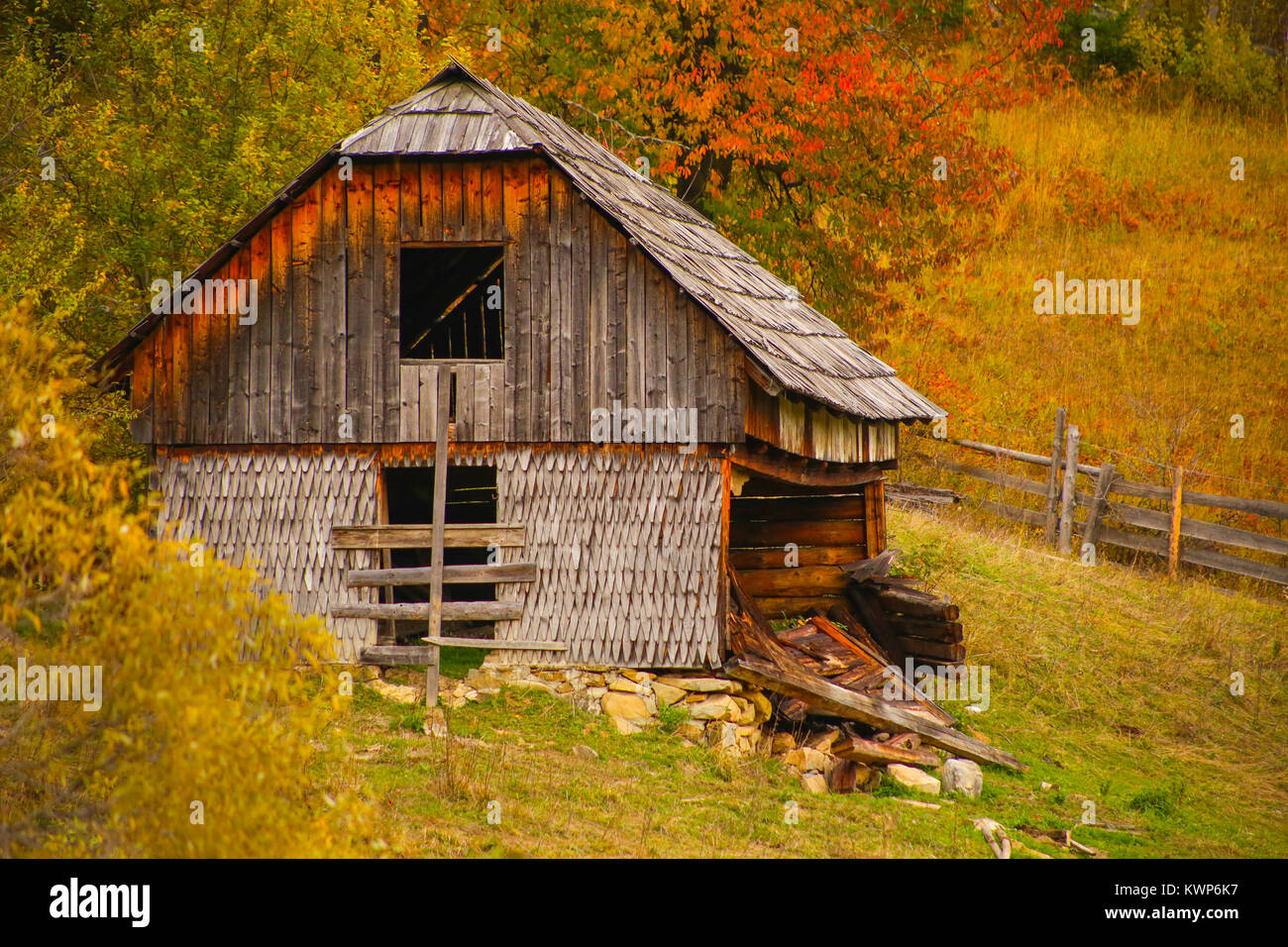 Autumn scenery landscape with colorful forest, wood fences and abandoned hay barn in Prisaca Dornei, Suceava County, Bucovina, Romania Stock Photo