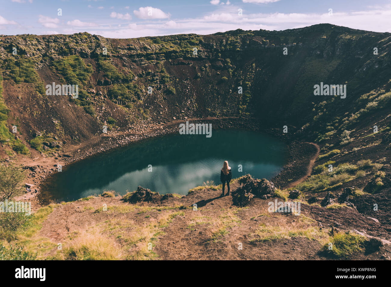back view of young woman looking at beautiful crater lake in Iceland  Stock Photo