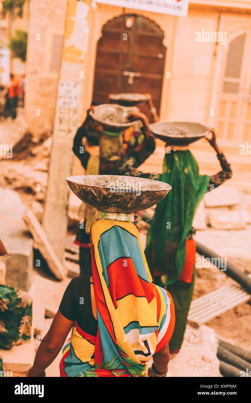 back view of women in bright traditional clothes carrying bowls on
