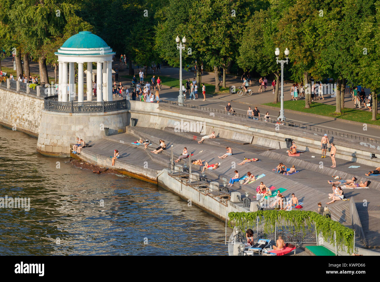 Unidentified people sunbathing at the Gorky Park at Moskva River bank on a sunny day. Moscow, Russia. Stock Photo