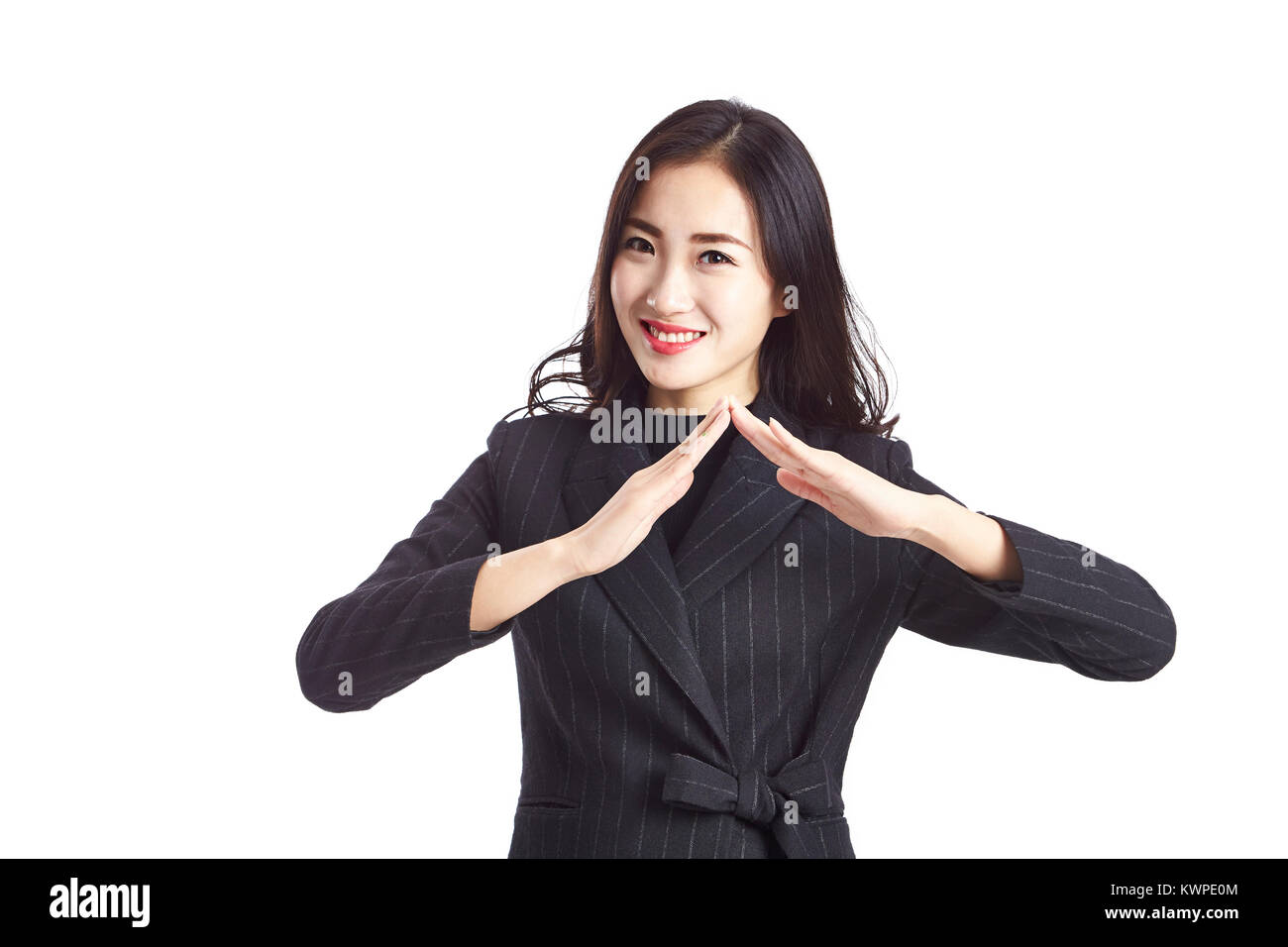 studio shot of a beautiful young asian businesswoman making a roof sign with hands, looking at camera smiling, isolated on white background. Stock Photo