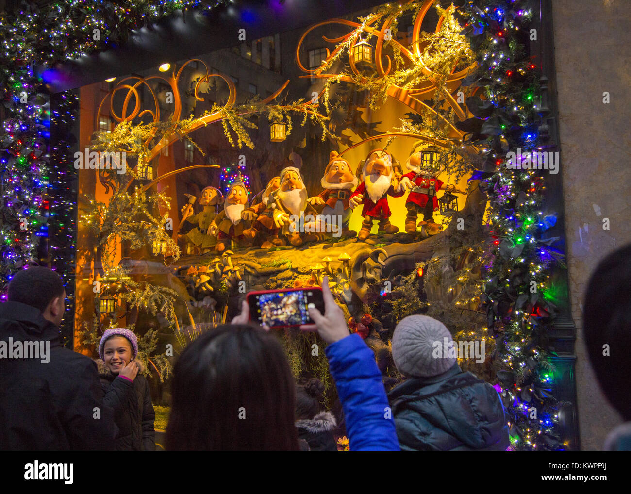 People take photos of 'The Seven Dwarfs'  in the Christmas holday display windows at Lord & Taylor on 5th Avenue in midtown Manhattan. Stock Photo