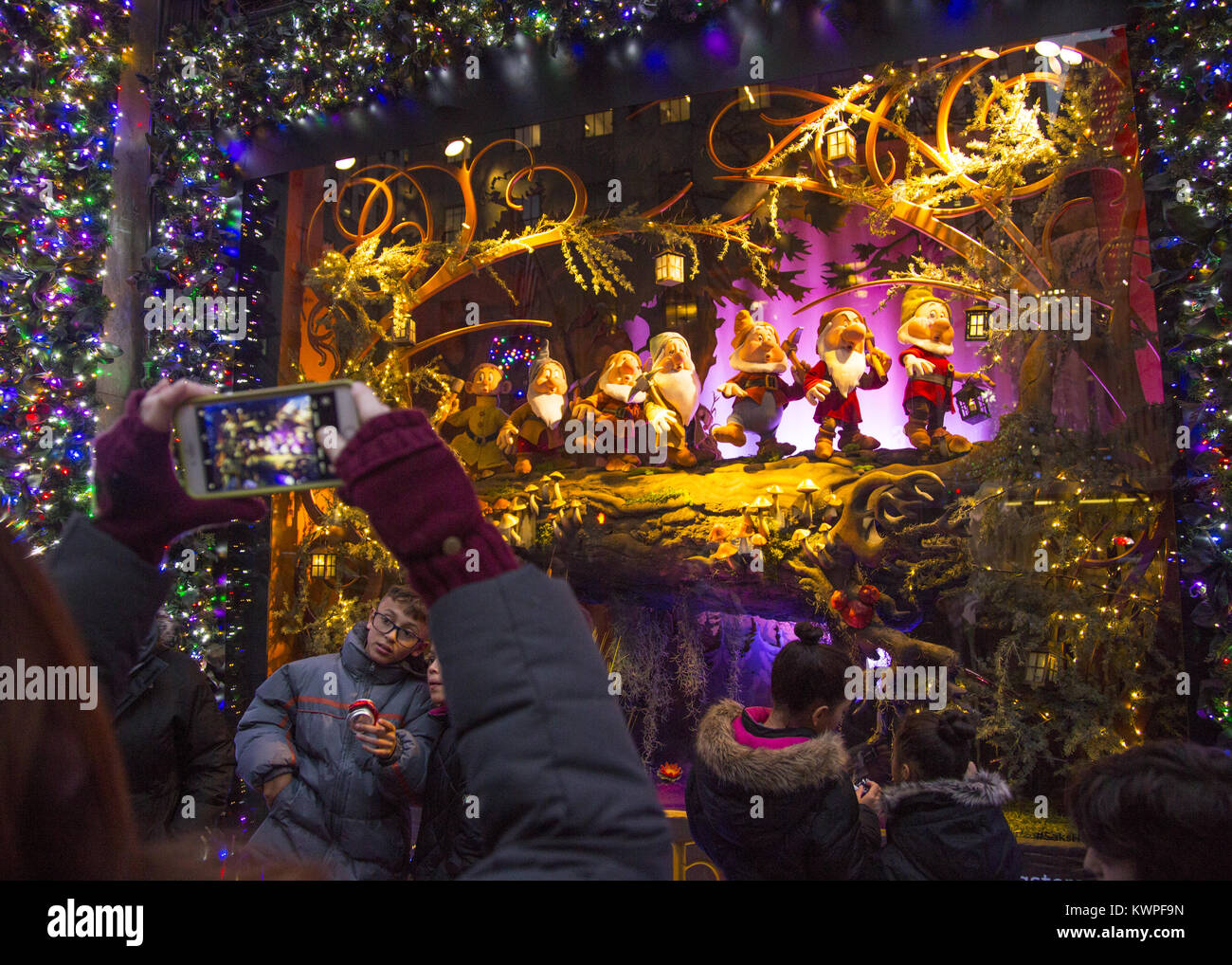 People take photos of 'The Seven Dwarfs'  in the Christmas holday display windows at Lord & Taylor on 5th Avenue in midtown Manhattan. Stock Photo