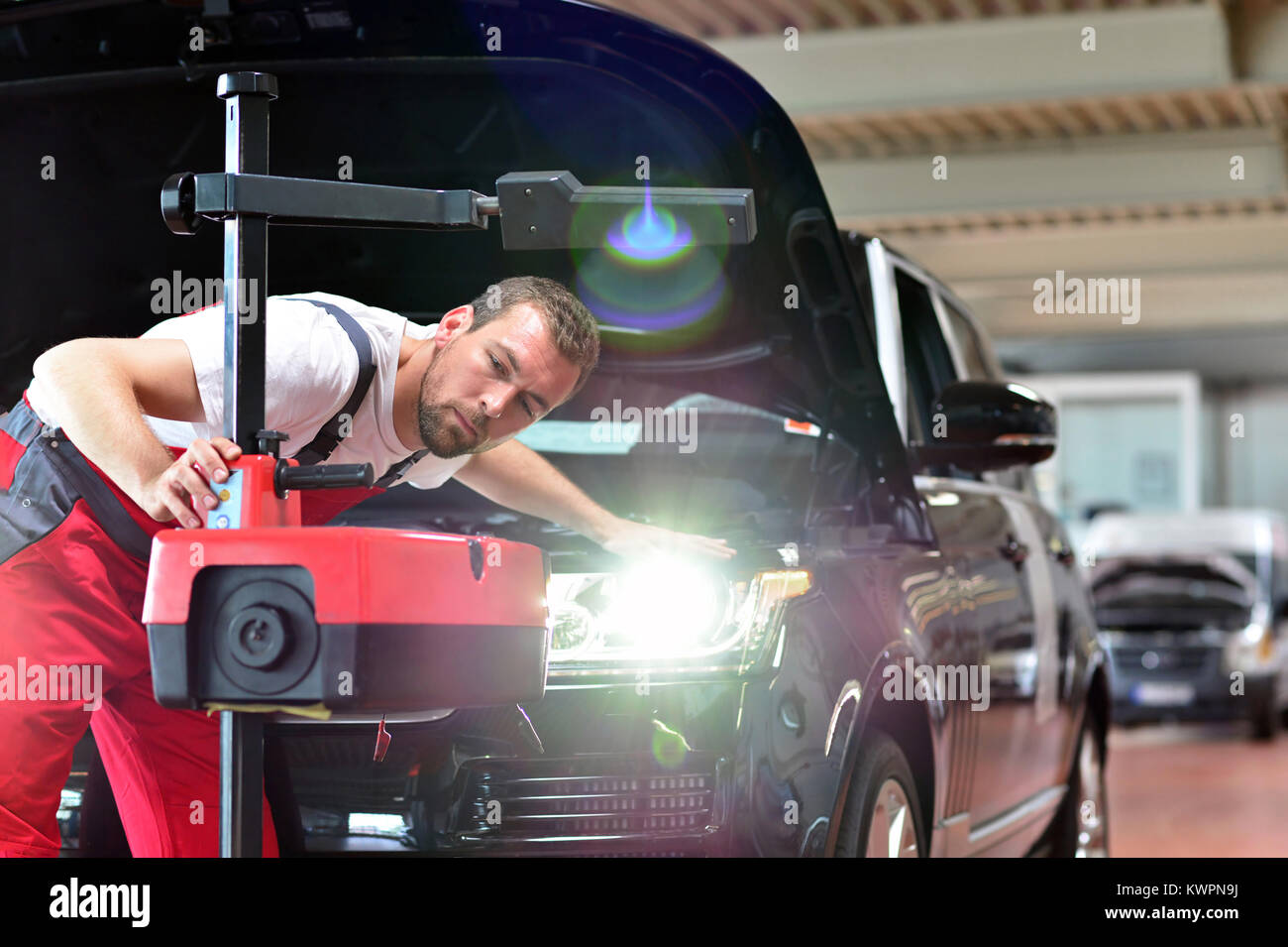 car repair shop worker checks and adjusts the headlights of a car's