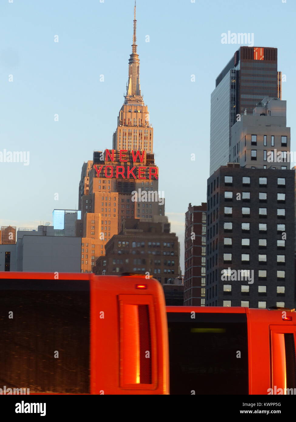 New York City's Empire State Building with red 'New Yorker' sign for Hotel New Yorker. and red Bolt buses. The 443 meters tall Empire State Building w Stock Photo