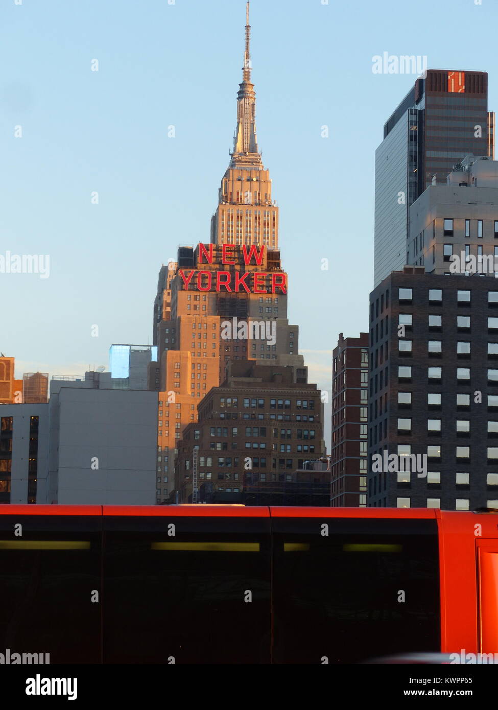 New York City's Empire State Building with red 'New Yorker' sign for Hotel New Yorker. and red Bolt buses. The 443 meters tall Empire State Building w Stock Photo