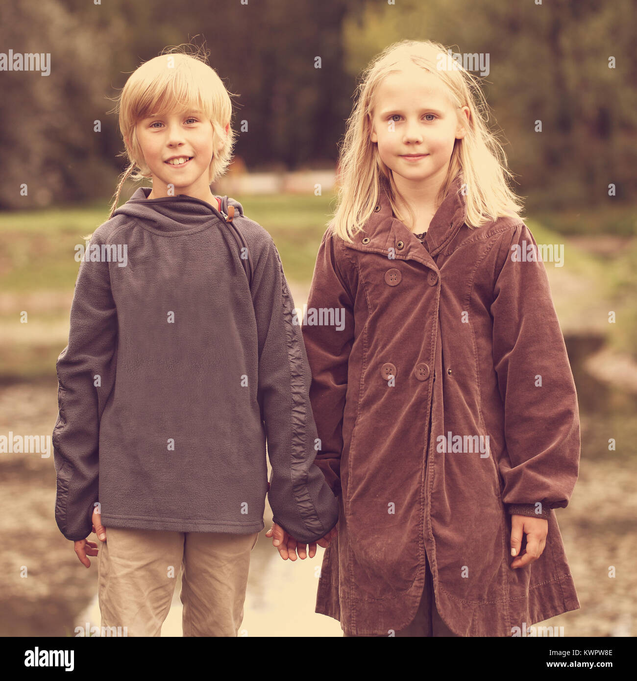 Happy kids outdoors, little boy and girl holding hands Stock Photo