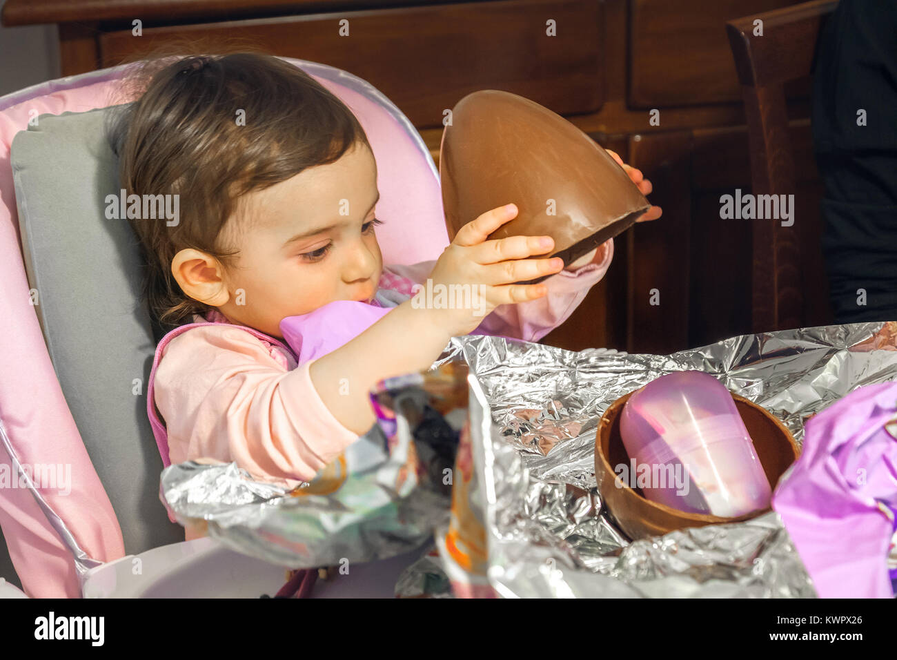 baby girl unwrap chocolate easter egg newborn Stock Photo