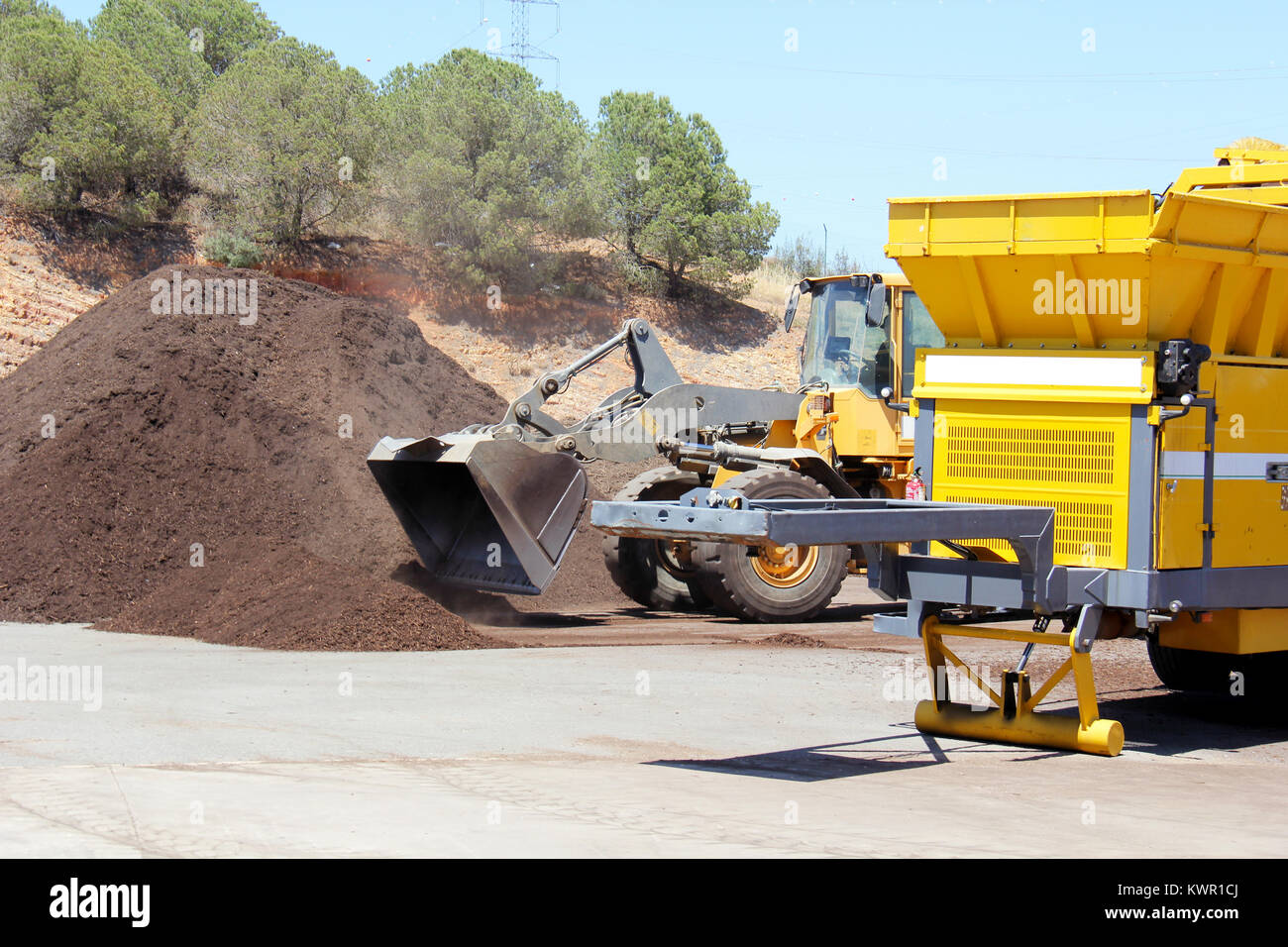 Industrial compost grinder fed by a bulldozer mulching garden waste