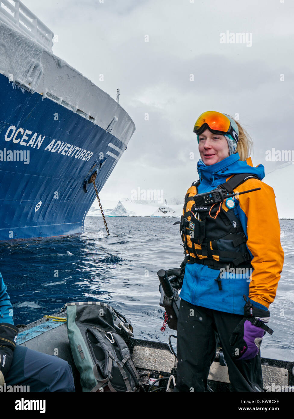 Guide & naturalist drives large inflatable Zodiac boat to shuttle alpine mountaineering skiers to Antarctica from the passenger ship Ocean Adventurer; Stock Photo
